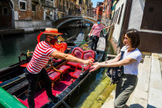 A gondolier (L) sprays sanitizer on a customer's hands prior to going for a gondola ride on a canal in Venice on June 12, 2020 as the country eases its lockdown aimed at curbing the spread of the COVID-19 infection, caused by the novel coronavirus.
