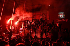 Liverpool fans celebrate outside Anfield in Liverpool, north west England on July 22, 2020 after Liverpool's final home English Premier League football match of the season against Chelsea after which the team was presented with the Premier League trophy. Liverpool on Wednesday lifted the Premier League trophy at the famous Kop stand at Anfield after their final home game of the season. With no fans able to attend due to the COVID-19 coronavirus pandemic, Liverpool said the idea for the trophy lift was to honour the club's fans, but Liverpool manager Jurgen Klopp urged fans to respect social distancing measures, after thousands gathered around the club's stadium and in the city centre following their coronation as champions last month.
