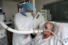 Christian George, Director of Research at the National Centre of Scientific Research, helps a patient suffering from COVID-19 to use the COVID-19 'Breathalyzer' test machine at the La Croix-Rousse Hospital in Lyon, France, July 22, 2020. 