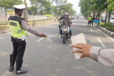 Enforcement: Jakarta Police officers stop motorcyclists at a checkpoint as part of Operation Patuh Jaya to ensure compliance with traffic rules and large-scale social restrictions (PSBB) in Cempaka Putih, Central Jakarta, on July 24.