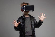 A boy uses a virtual reality (VR) headset in this stock image.