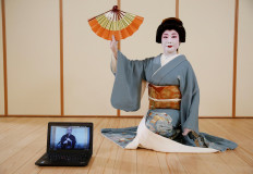 Tokijyo Hanasaki, a jiutamai dancer, poses for a photograph behind a laptop playing a musical performance which was filmed in advance in order to avoid physical contact, to accompany  Hanasaki's dance performance for a film being made that is supported by the Tokyo Metropolitan government in order to support artists during the coronavirus disease (COVID-19) outbreak, at a studio in Tokyo, Japan, June 29, 2020. Reuters/Kim Kyung-Hoon 