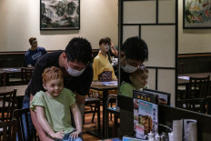 Restaurant owner Masato Takemine moves one of his mannequins, used as a method to maintain social distancing among diners, onto another seat at his restaurant in the Akabane district of Tokyo on July 26, 2020, amid the COVID-19 coronavirus pandemic.
