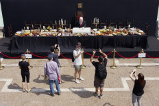 People visit a protest art installation depicting Israeli Prime Minister Benjamin Netanyahu sitting on a table for the 'Last Supper', by Israeli artist Itay Zalait, on July 29, 2020 at Rabin Square in Tel Aviv as protests demanding Netanyahu's resignation are growing by the week.
