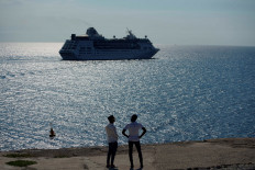Men watch the cruise ship MS Empress of the Seas, operated by Royal Caribbean International, as it leaves the bay of Havana, Cuba, June 5, 2019. 