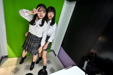 This photo taken on July 21, 2020 shows teenagers posing at a Japanese style photo booth known locally as 'purikura', or print club, in Tokyo. 
