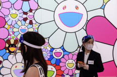 This photo taken on July 30, 2020 shows staff members wearing face shields next to 'Pop up flower' by artist Takashi Murakami during a media preview of 'STARS: Six Contemporary Artists from Japan to the World' at the Mori Art Museum in Tokyo.