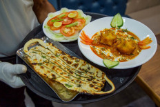 A waiter carries 'Covid Curry' and 'Mask Naan', two COVID-19 coronavirus-themed dishes, to serve to customers at their restaurant in Jodhpur on August 3, 2020.