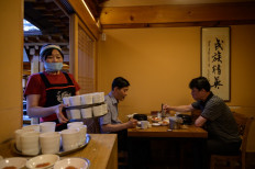 Customers eat a chicken and ginseng soup known as 'samgyetang',' at the Tosokchon Samgyetang restaurant in Seoul on July 16, 2020. 