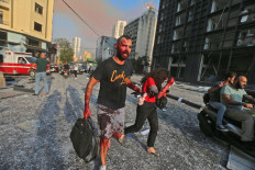 Wounded people walk near the site of an explosion at the port in the Lebanese capital Beirut on August 4, 2020. - Two huge explosion rocked the Lebanese capital Beirut, wounding dozens of people, shaking buildings and sending huge plumes of smoke billowing into the sky. Lebanese media carried images of people trapped under rubble, some bloodied, after the massive explosions, the cause of which was not immediately known. AFP/Str