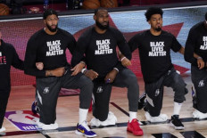 (L-R) Anthony Davis #3, LeBron James #23 and Quinn Cook #28 of the Los Angeles Lakers take a kneel before an NBA basketball game against the Toronto Raptors at The Arena in the ESPN Wide World Of Sports Complex on August 1, 2020 in Lake Buena Vista, Florida.