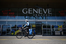 A man wearing a protective face mask rides his bicycle past the entrance of Geneva Airport amid the COVID-19 outbreak, caused by the novel coronavirus, on May 28, 2020, in Geneva. 