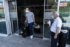 A traveler, mask-clad due to the COVID-19 coronavirus pandemic, leaves on August 1, 2020 the arrivals hall of Larnaca International Airport to catch a cab in Cyprus, a former UK colony that depends heavily on tourism. 