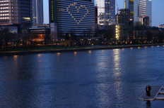 A couple stands on a landing stage on river Main opposite to a hotel with its window lights illuminated in the shape of a heart after German Chancellor Angela Merkel addressed the nation on the consequences of the spread of the coronavirus disease (COVID-19) in Frankfurt, Germany, on March 22, 2020. 