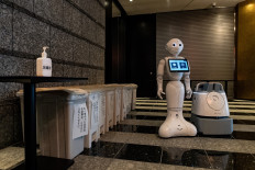 A greeting robot called Pepper (C) and a cleaning robot called Whiz (R) stand in the lobby of a hotel during the first day the building is used as a new medical lodging facility to accommodate COVID-19 coronavirus patients with mild symptoms in Tokyo on May 1, 2020. 