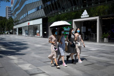A group of women wearing face masks walk along a road at a business district in Beijing on August 11, 2020.
