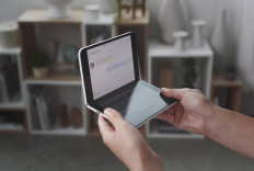 This handout photo obtained October 2, 2019 courtesy of Microsoft shows a woman looking at a new dual-screen device Surface Duo. 