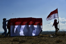 The youth of state defense carry Indonesian flags to commemorate 75th Indonesia's Independence Day which falls on August 17, at a mountain of garbage in Banda Aceh on August 16, 2020. 