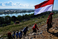 The youth of state defense carry an Indonesian flag to commemorate 75th Indonesia's Independence Day which falls on August 17, at a mountain of garbage in Banda Aceh on August 16, 2020. 