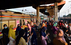 Face mask-clad commuters wait for their train at the Tanah Abang railway station in Jakarta on Aug. 18, 2020. 