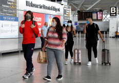 Travellers, some wearing a face mask or covering due to the COVID-19 pandemic, walk through the terminal building at London Stansted Airport, northeast of London on August 20, 2020 following the decision by British no-frills airline Easyjet to close its operations at the airport from August 31.
