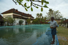 In this picture taken on August 23, 2020, a member of resort staff feeds fish in a swimming pool that has been turned into a fish farm at Aveda Resort in Kumarakom, in Kerala state. 
