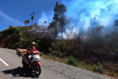 A motorcyclist passes a road as a forest fire rages in Kerinci, Jambi, on Aug. 8, 2020.