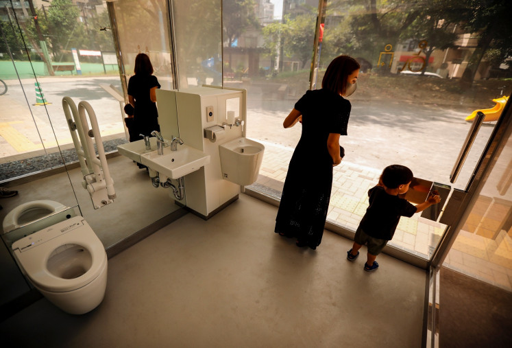 A mother and her son check out the transparent public toilet that becomes opaque when occupied, designed by Japanese architect Shigeru Ban, at Yoyogi Fukamachi Mini Park in Tokyo, Japan August 26, 2020.