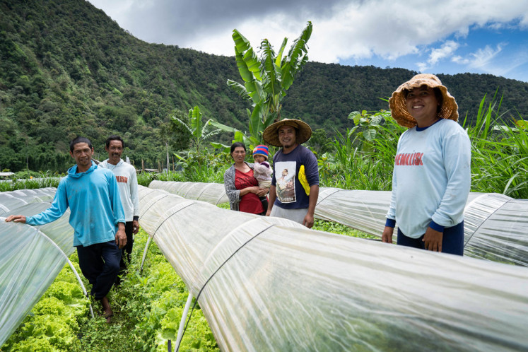  Farmer partners of TaniHub pose for a picture while standing among a lettuce farm in Bedugul, Bali.