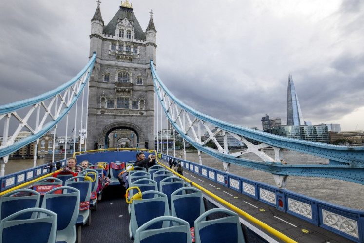 A man takes pictures on Tower Bridge from the near empty top of an open top tourist tour bus in central London on August 24, 2020. 