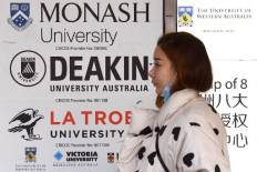 A woman walks past signage for Australian universities in Melbourne's central business district on June 10, 2020, as Australian officials and leading universities rejected China's claims students should be 