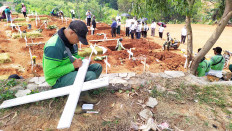 A gravedigger writes the name of a deceased COVID-19 victim on a cross at Pondok Ranggon public cemetery in East Jakarta.