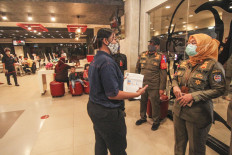 Public Order Agency officers announce new shop closing hours in Margonda, Depok, West Java, in August 2020.