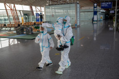 Passengers in full protective suits make their way to their gate at terminal three in Beijing's Capital International Airport which is nearly empty due to the COVID-19 coronavirus outbreak in Beijing on June 30, 2020.