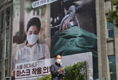 A man walks past a banner advocating mandatory mask wearing in front of Seoul City Hall in Seoul on September 4, 2020. - South Korea reported 198 new Covid-19 cases on September 4, the 22nd consecutive day of triple-digit increases, driven by several clusters, many of them linked to Protestant churches in the Seoul region. 