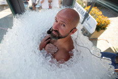Austrian sportsman Josef Koeberl looks on as he stands still in an ice-filled glass cabin trying to set a World Record of staying in ice, in Melk, Austria, on September 5, 2020.