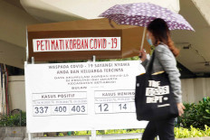 Morbid reminder: A woman walks by a fake coffin near Jl. Setiabudi in South Jakarta on Sept. 7. The display is part of the district’s campaign to promote compliance with COVID-19 health protocols.