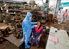 A healthcare worker wearing personal protective equipment (PPE) takes a swab sample from an employee for a rapid antigen test inside a factory, amidst the coronavirus disease (COVID-19) outbreak, in Ahmedabad, India, on Sept. 11.