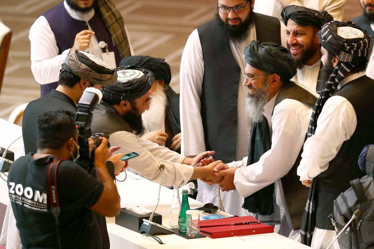 Taliban delegates shake hands during talks between the Afghan government and Taliban insurgents in Doha, Qatar September 12, 2020. 