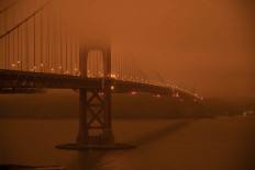 Cars drive along the Golden Gate Bridge under an orange smoke filled sky at midday in San Francisco, California on September 9, 2020. - More than 300,000 acres are burning across the northwestern state including 35 major wildfires, with at least five towns 