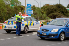 A police officer directs a driver wanting to leave the city at a COVID-19 check point setup at the southern boundary in Auckland on Aug.14. New Zealand rushed to track the source of a sudden return of the coronavirus as the number of new cases in its biggest city rose to 17 and officials warned more infections were inevitable.

