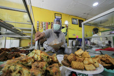 A woman wearing a protective mask prepares a takeaway order at a food stall in Jakarta on Monday as the city returns to full large-scale social restrictions (PSBB) after a spike in infections.