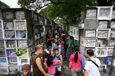 People light candles and pray for their relatives at a cemetery during the annual observance of All Saint's Day in Manila on November 1, 2019. 