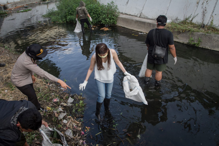 Public Order Agency (Satpol PP) officers handle COVID-19 protocols violators by telling them to clean a river during a raid in Banjarsari, Surakarta, Central Java on Sept. 16.