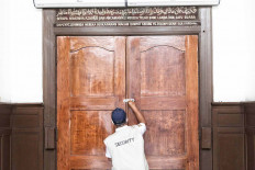 Temporarily closed: A security officer locks the doors of Cut Meutia Mosque in Central Jakarta on Thursday. The city administration has reimposed large-scale social restrictions to combat a COVID-19 spike in the capital that has strained hospital resources.