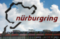 This file photo taken on July 6, 2013 shows spectators standing on a hotel balcony behind the logo of the Nuerburgring racetrack, featuring a graphic representation of the circuit, during the qualifying session at the Nurburgring race track in Nuerburg, western Germany, ahead of the German Formula One Grand Prix. Germany's Nurburgring can welcome up to 20,000 fans next month when it hosts Formula One, organizers said Monday, after local authorities gave it the go-ahead alongside stringent health measures.

