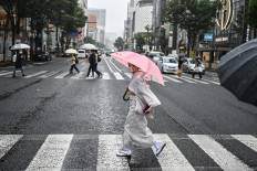 A woman wearing traditional dress uses an umbrella to shelter from the rain while crossing a street in Tokyo on September 24, 2020.
