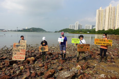 Lance Lau, 11, Elise Hon, 11, Rose Netherton, 36, and other climate activists hold placards as they pose for pictures during a climate strike and a beach clean-up at San Tau Beach on Lantau island in Hong Kong, China on Sept. 25, 2020.