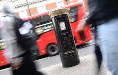 Pedestrians walk past a Royal Mail postbox, painted black instead of traditional red, to honor Black Britons, as part of the forthcoming Black History Month, in Brixton, London, Britain, on September 30, 2020. 