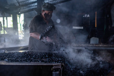 This picture taken on September 29, 2020 shows a worker transferring pre-sweetened black coffee for cooling at the Antong Coffee Factory in Taiping in the Malaysian state of Perak. 